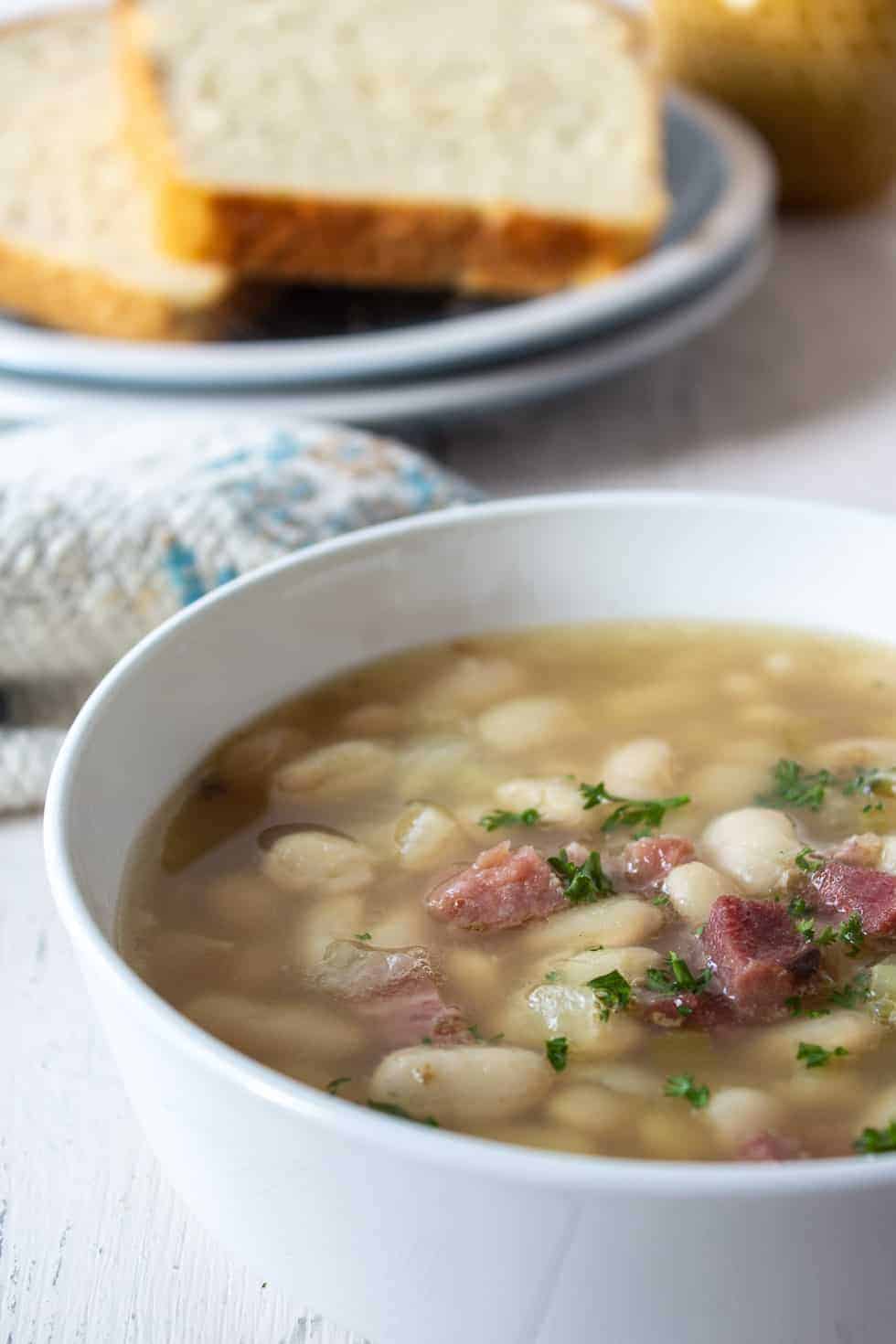 A bowl of soup with white beans and ham.