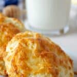 Cheesy biscuits on a white plate with a glass of milk in the background.
