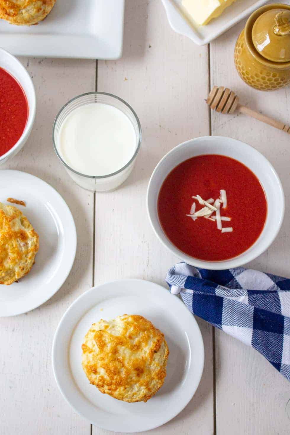 A table filled with soup, biscuits and a glass of milk. 