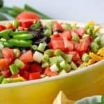 A yellow dish filled with a dip topped with fresh cut tomatoes and green onions.