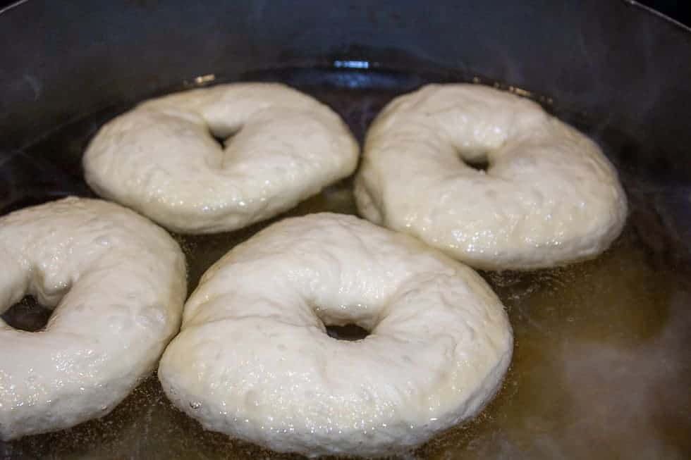 Bagels boiling in a pot of hot water.
