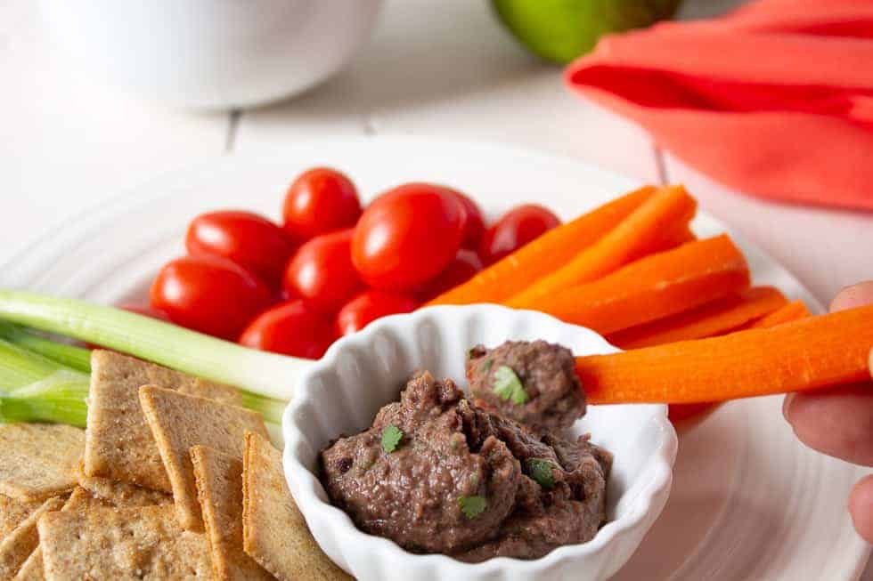 A carrot stick with black bean dip on the end of the carrot..