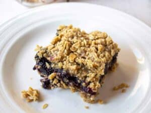 Oatmeal bars with a blueberry filling cut into a square piece.