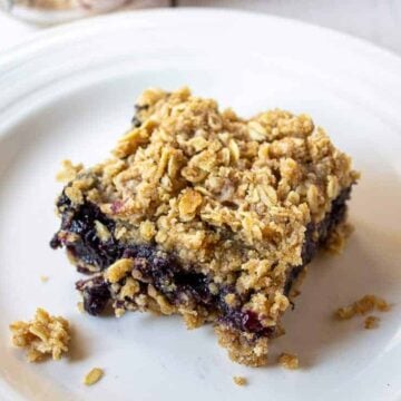 Oatmeal bars with a blueberry filling cut into a square piece.