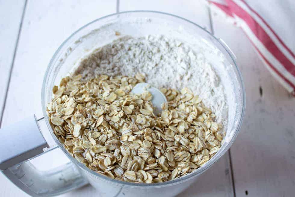 Old fashioned oats added to a mixture in a food processor bowl.