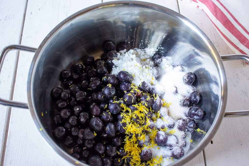 Blueberries with sugar, and lemon zest in a pot.