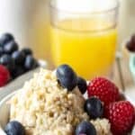 Oatmeal topped with fresh fruit in a white bowl.