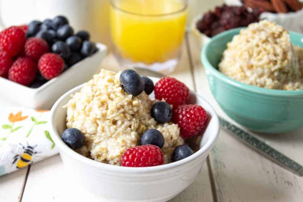 A bowl filled with a hot cereal and topped with fresh blueberries and raspberries.