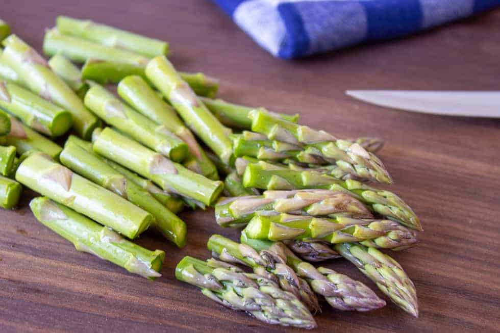 Chopped asparagus on a wooden cutting board.