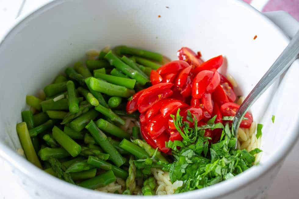 Fresh chopped tomatoes along with asparagus in a bowl.