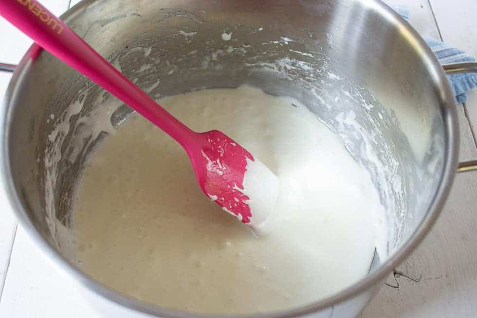 Melted marshmallows in a pot with a pink spatula.