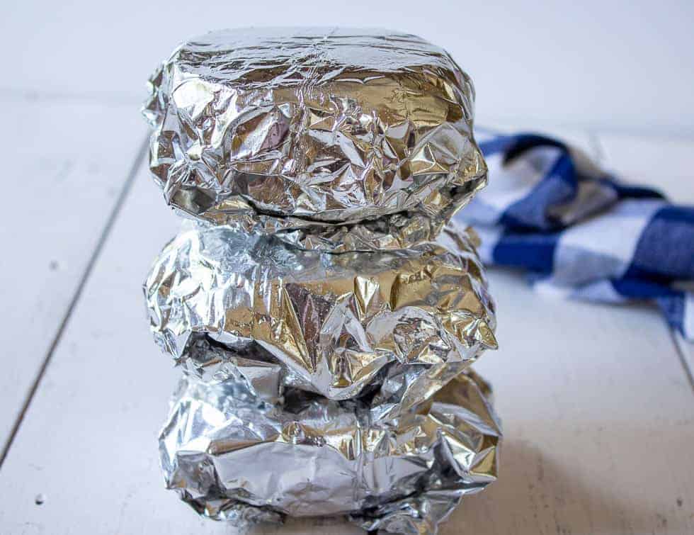 Sandwiches wrapped in foil and stacked on top of each other. 