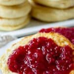 Toasted muffin on a plate covered with raspberry jam.