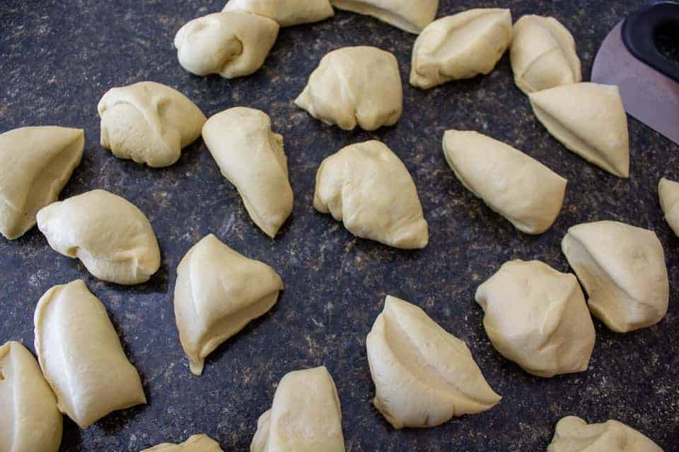 Cut pieces of dough on a black counter.