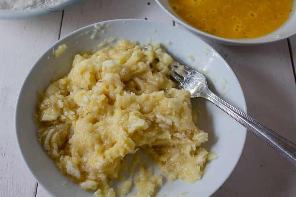 Mashed bananas in a bowl with a fork.