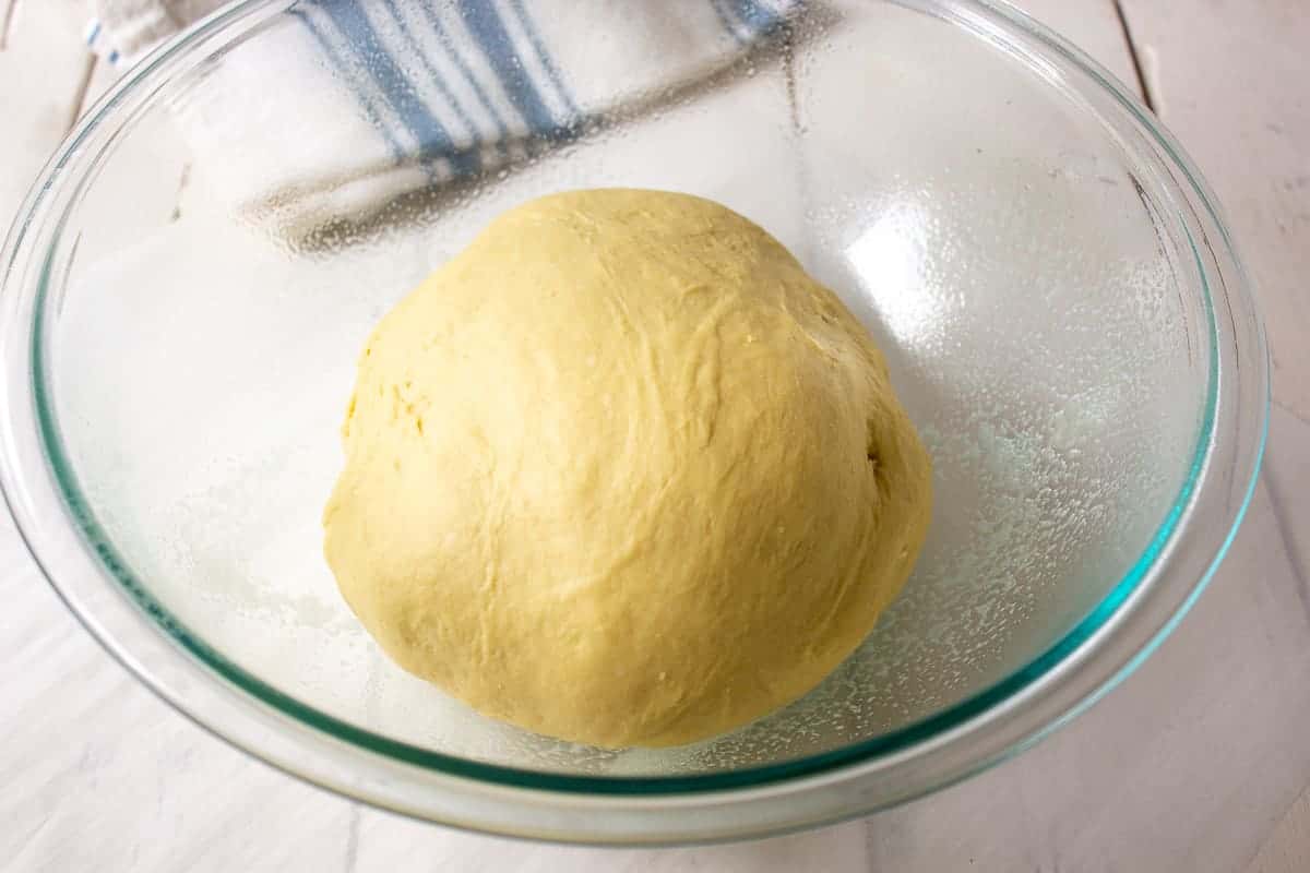 Unrisen bread dough in a glass bowl.