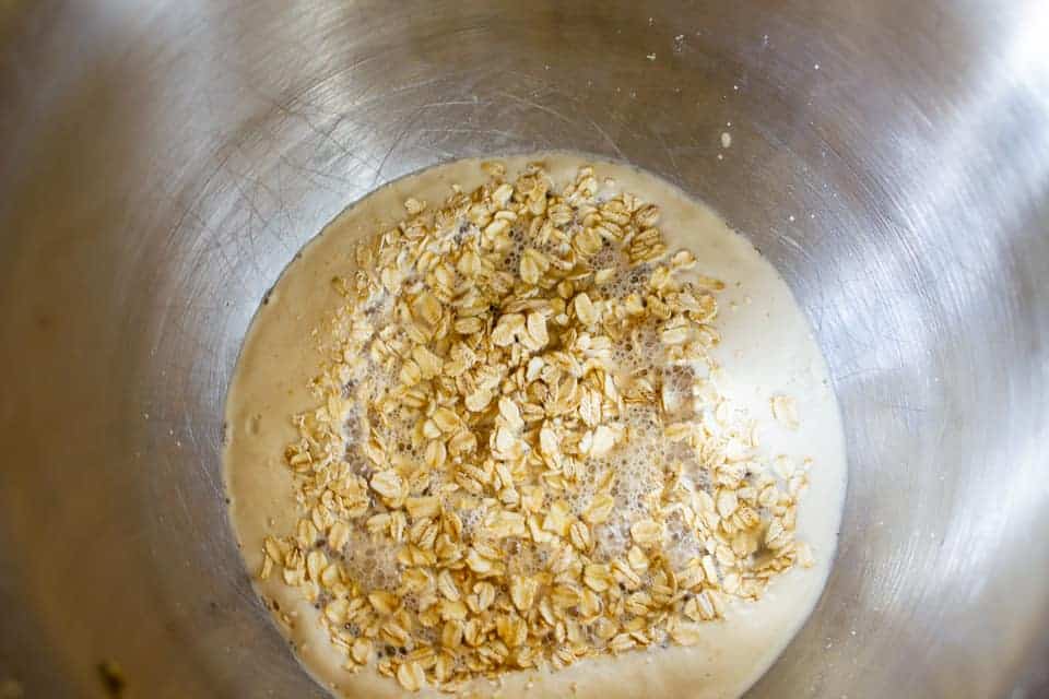 A mixing bowl with oats on top of a creamy mixture.