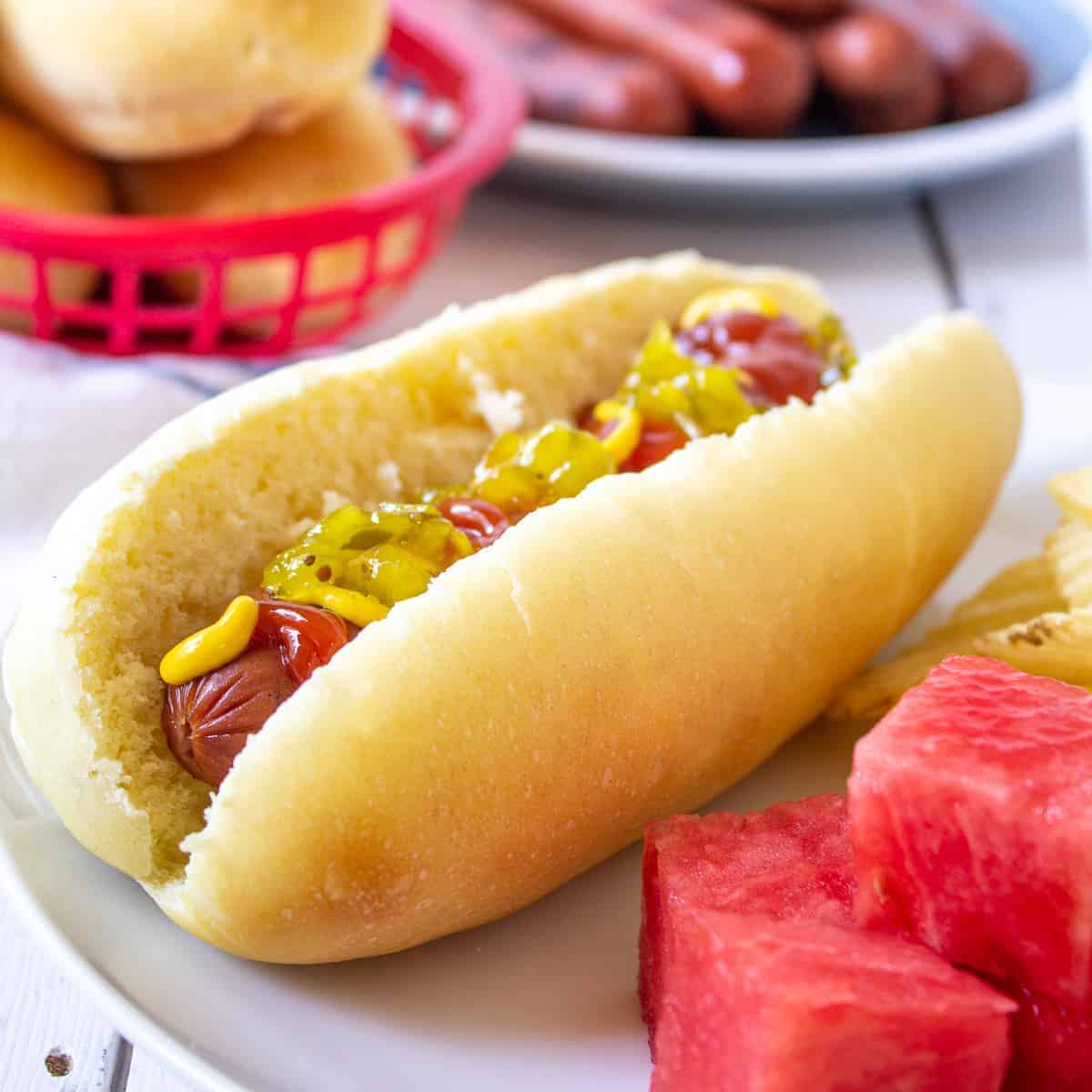 A hot dog bun with a hot dog topped with condiments.