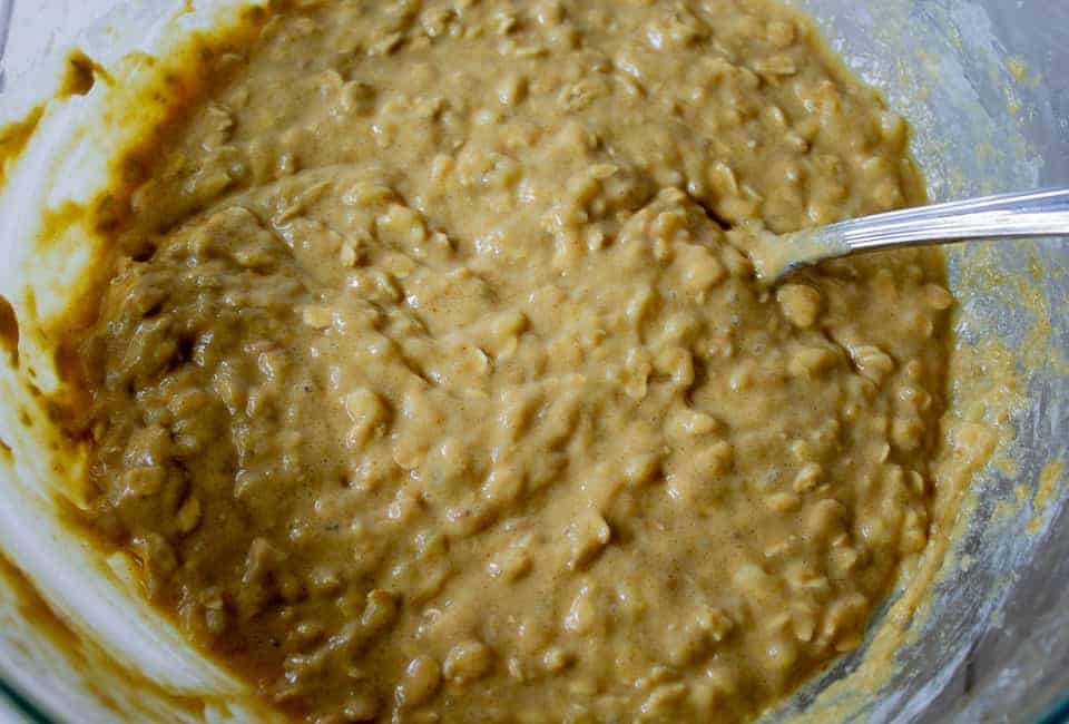 Oatmeal Banana Bread batter in a glass bowl with a spoon.