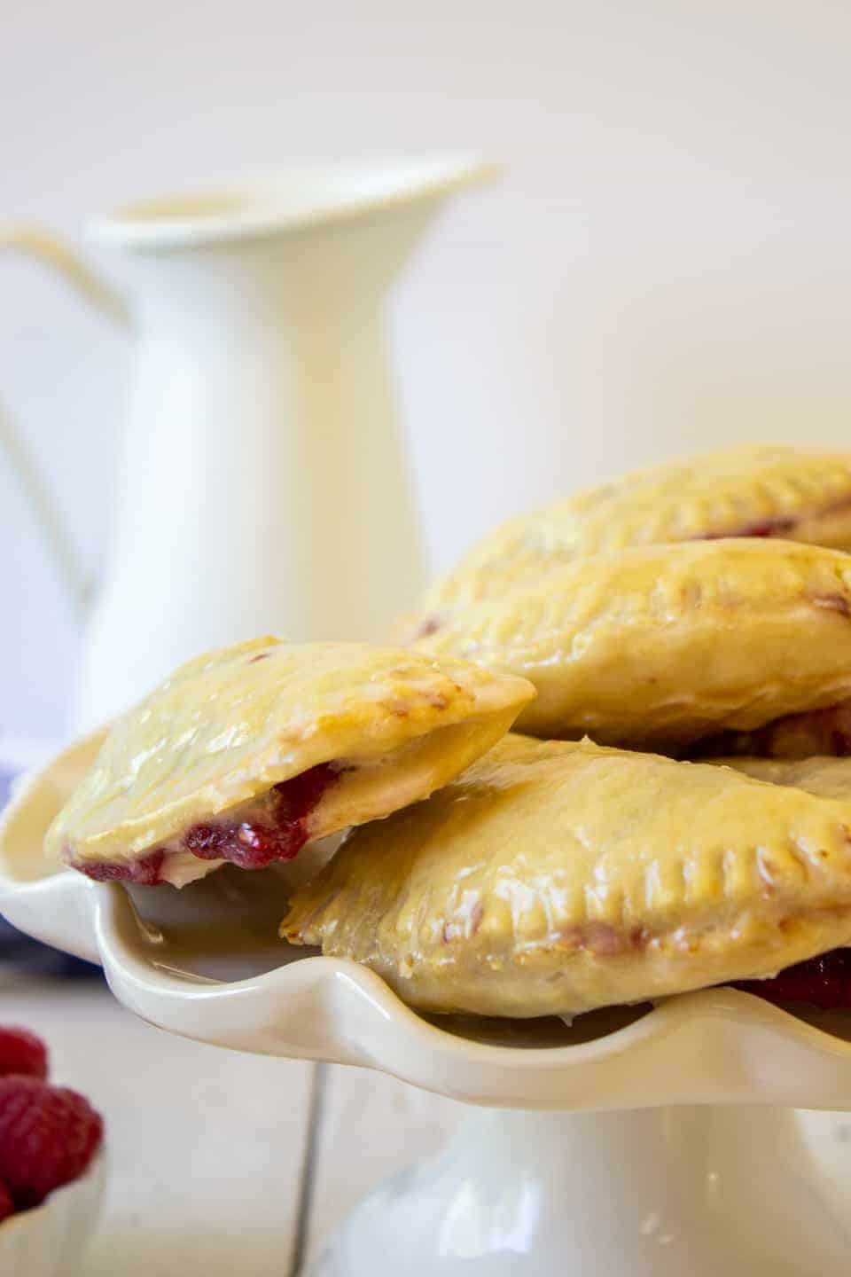 Hand pies stacked on a white cake plate. 