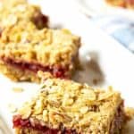 Oat bars filled with raspberry jam on a white platter.