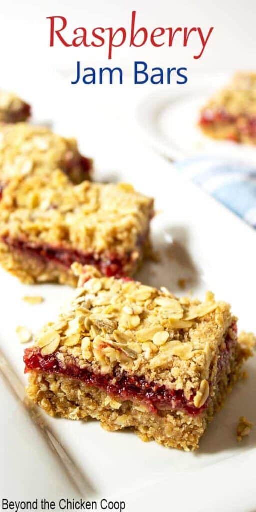 Oat bars filled with raspberry jam on a white platter.