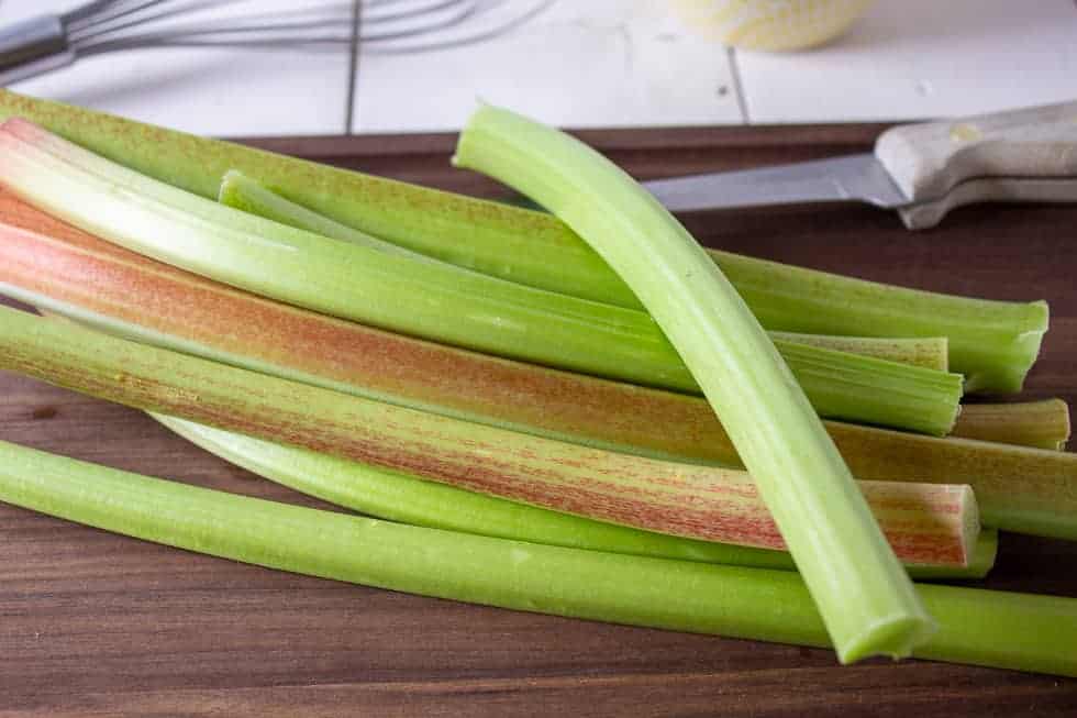 Stalks of rhubarb on a wooden cutting board. 