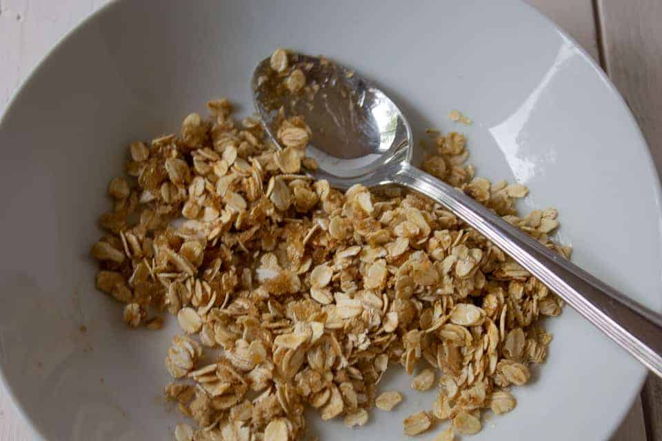 Oat mixture combined in a bowl with a spoon.