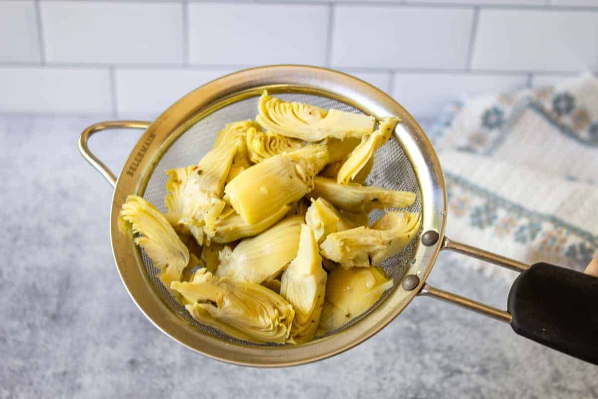 Artichoke hearts in a metal sieve.