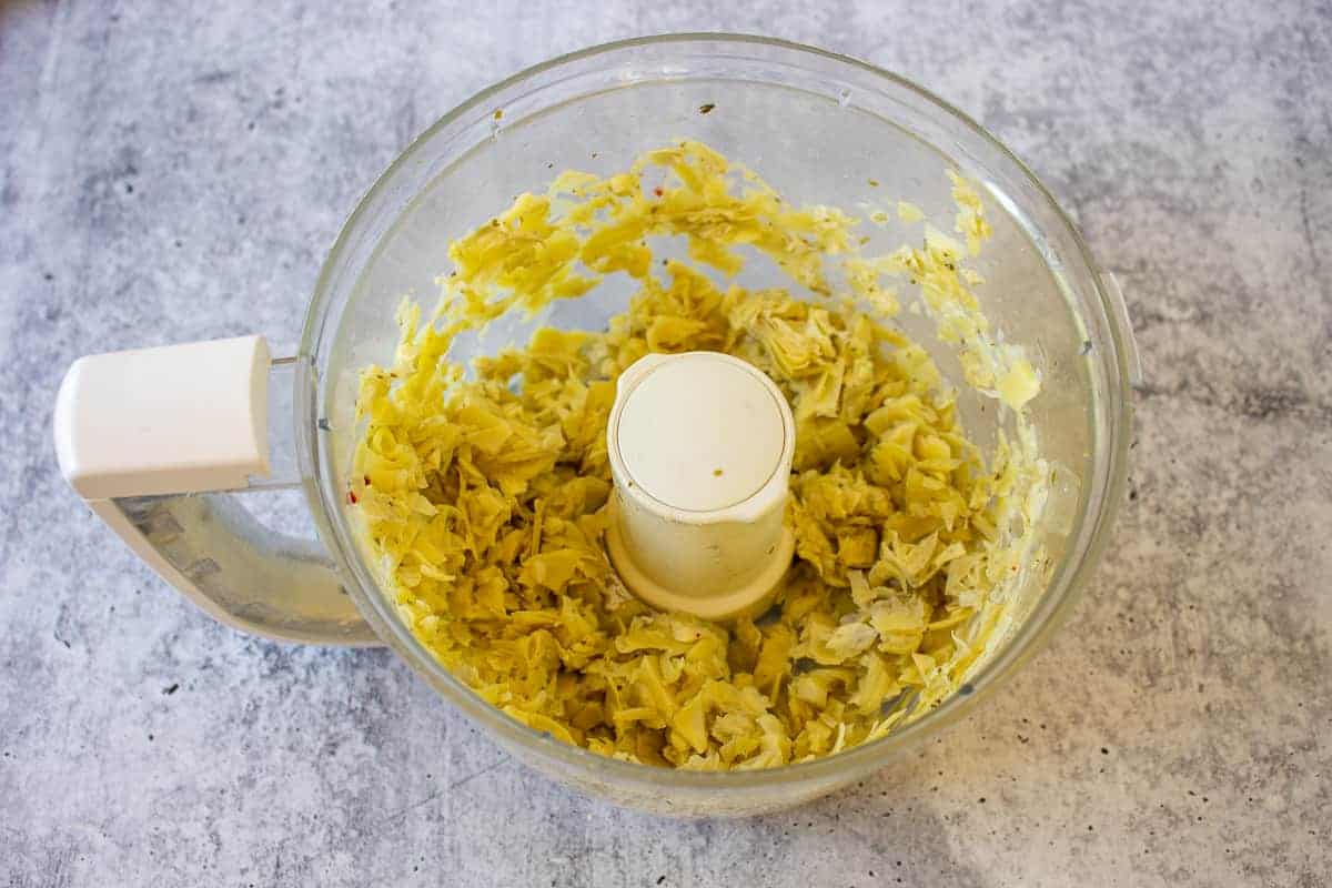 Chopped artichoke hearts in a food processor.