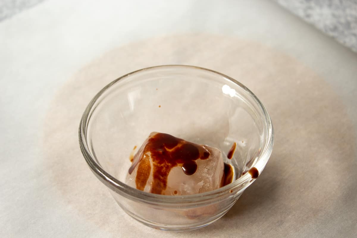 Chocolate sauce poured on top of an ice cube.