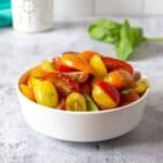 A white bowl filled with colored tomatoes.