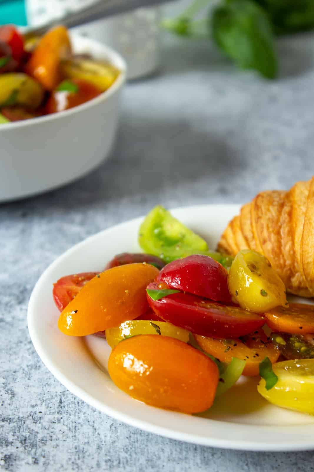 Tomato salad next to a sandwich.