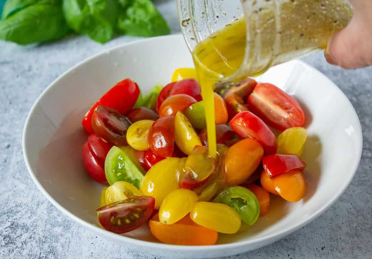 Vinaigrette being poured over cut tomatoes.