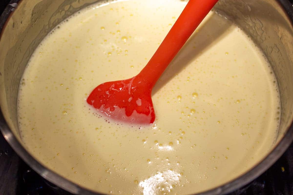 Cream mixture for ice cream in a pot with a red spatula.