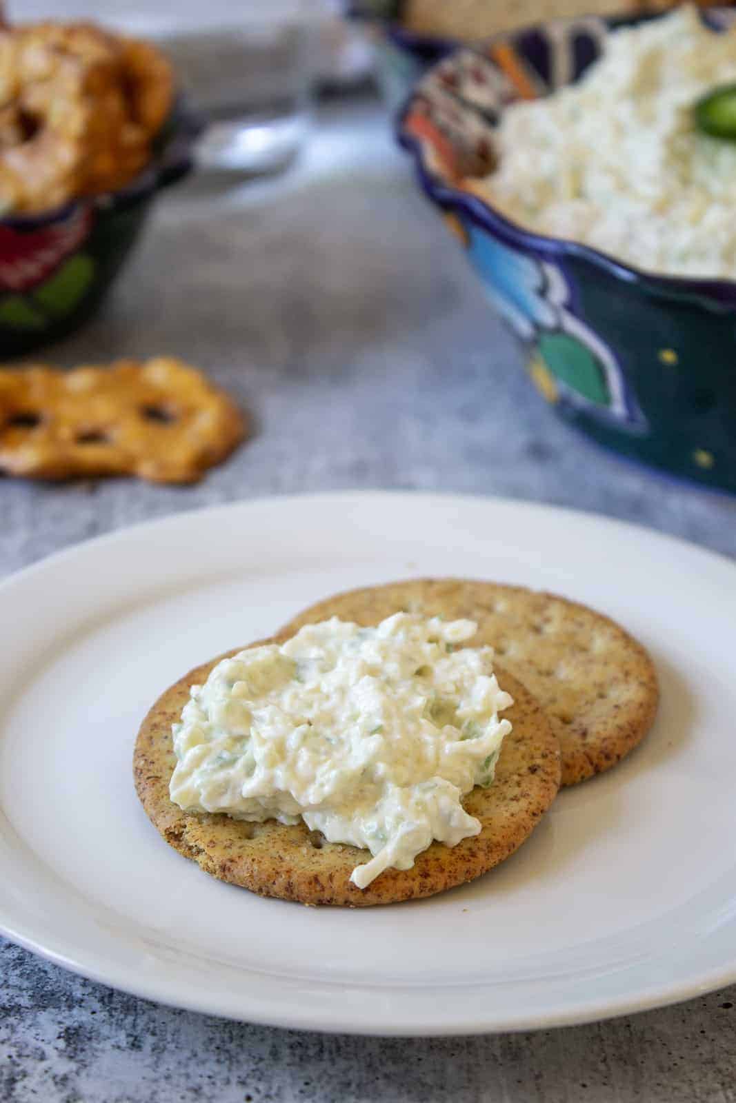 Artichoke dip spread on a multigrain cracker.