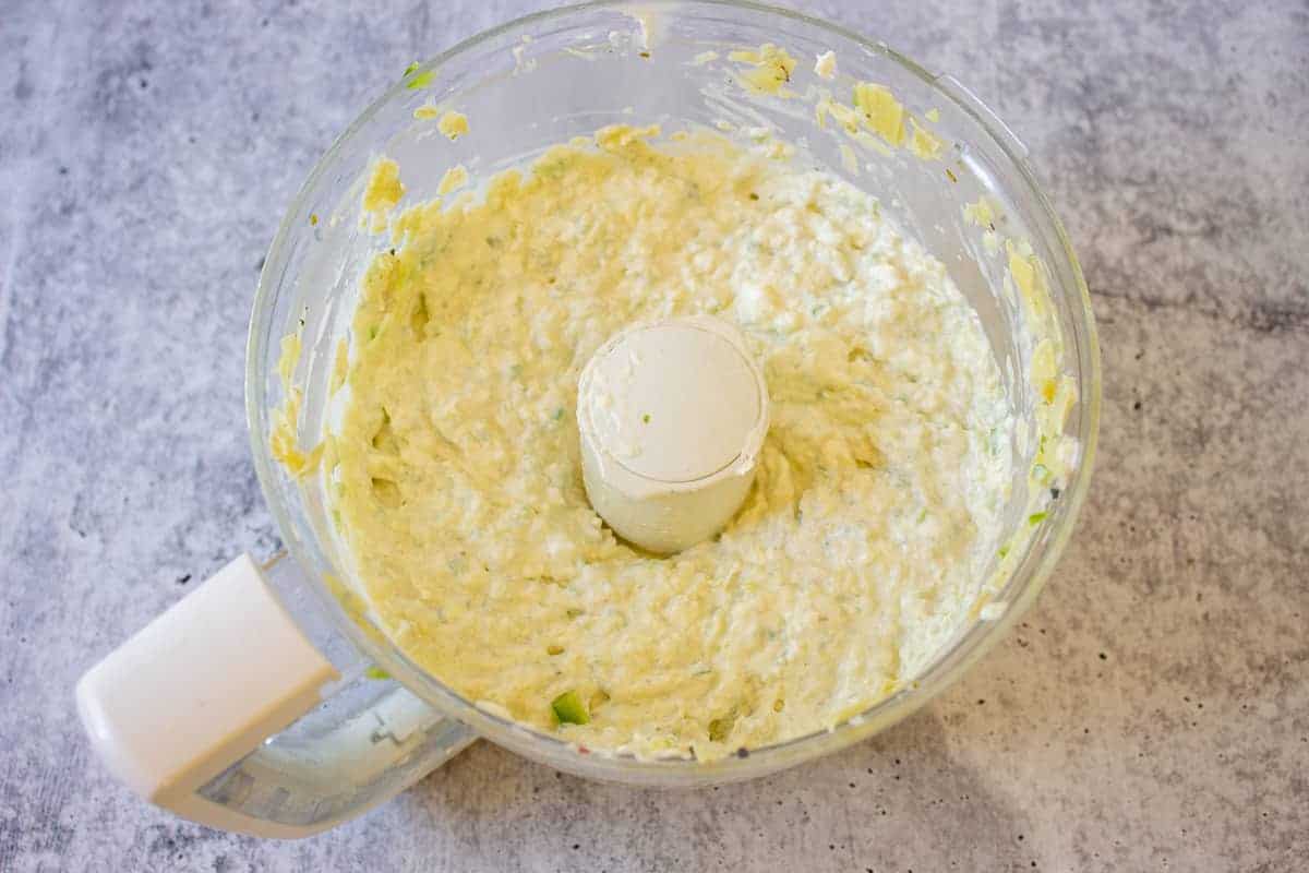 Artichoke dip with jalapenos in a food processor bowl.