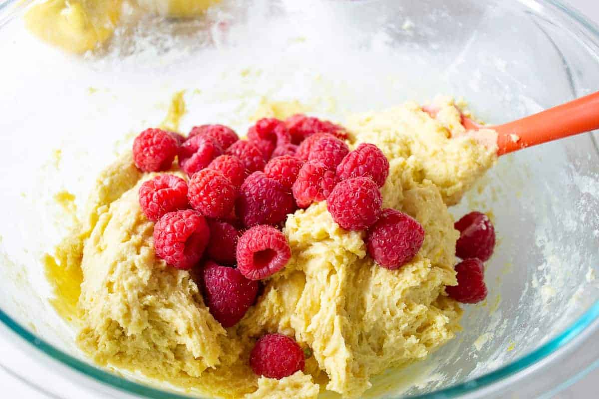 Fresh raspberries on top of a bowlful of muffin batter.