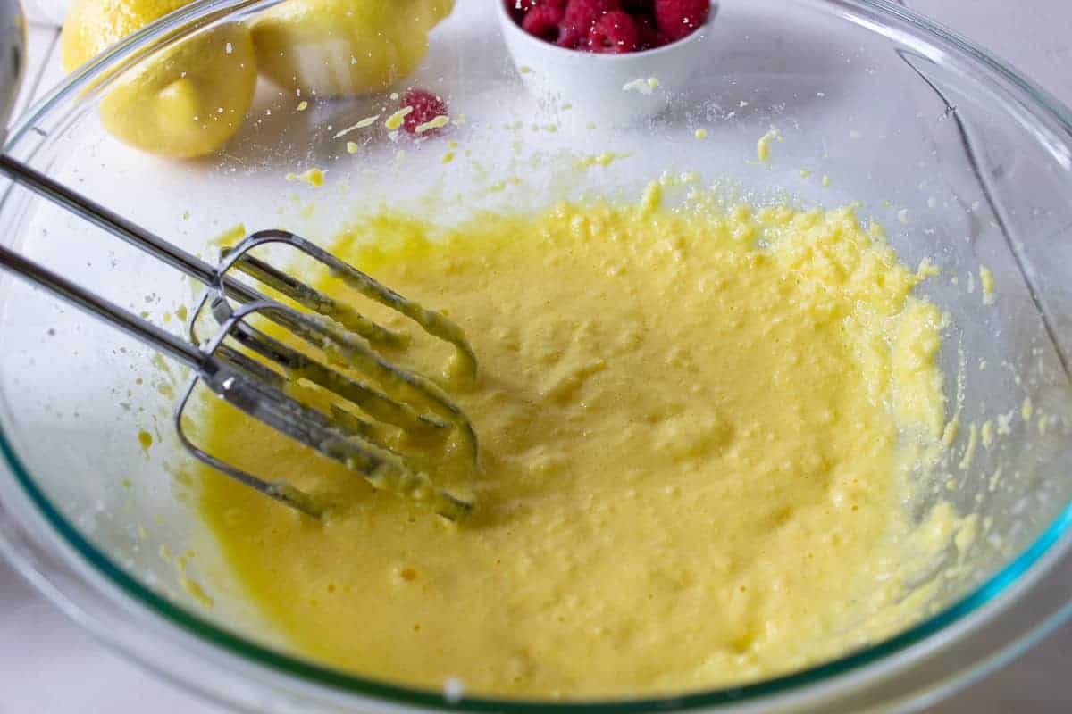 Muffin batter with electric beaters in a glass bowl.