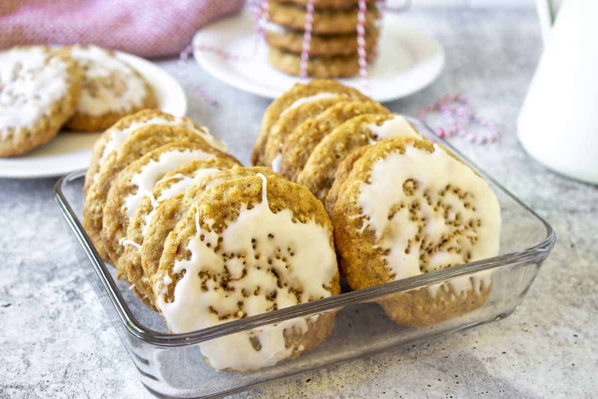 Iced cookies stacked in a glass container.