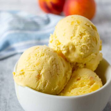 Scoops of peach ice cream in a small white bowl.