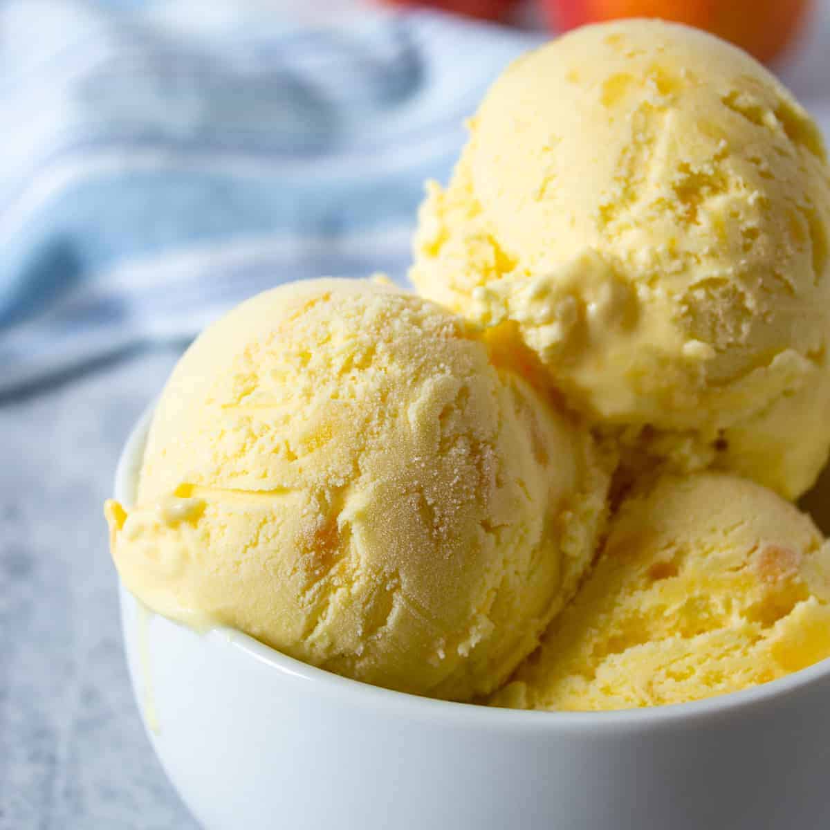 Scoops of peach ice cream in a white bowl.