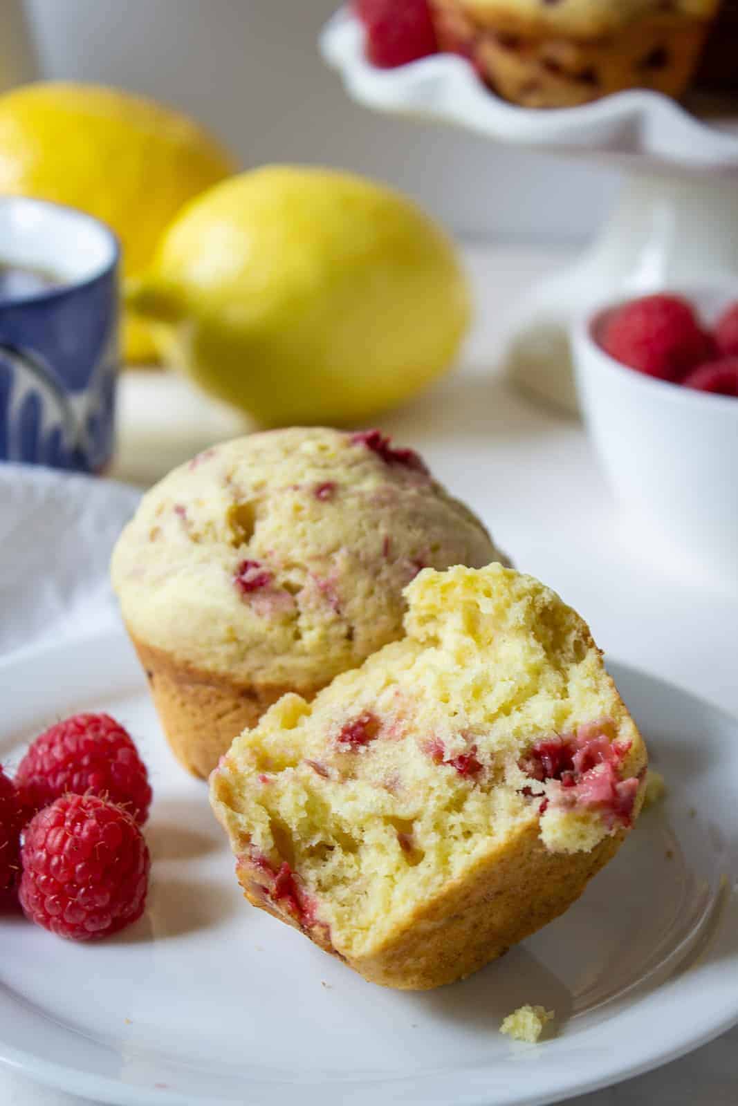 Raspberry muffins on a small plate with a few fresh raspberries next to the muffins. 