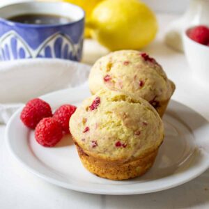 Two muffins with raspberries on a small white plate.