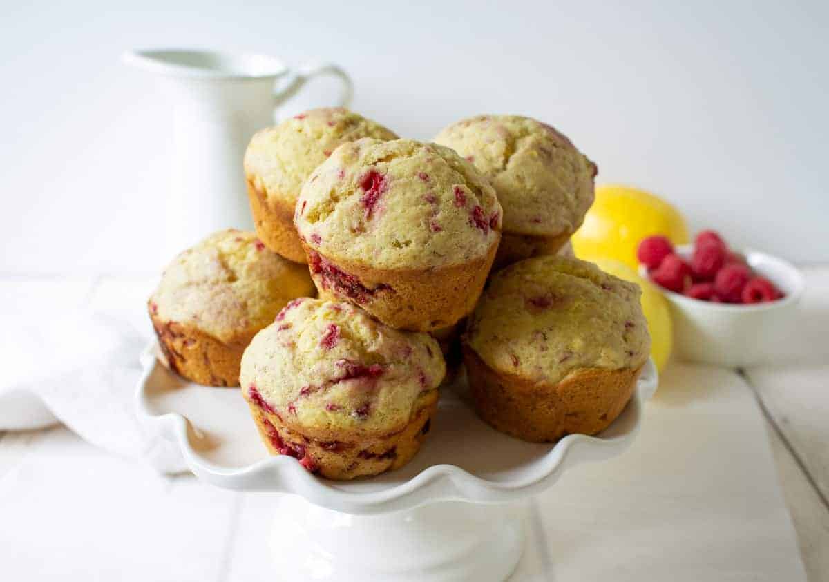 Muffins stacked on a white cake plate.