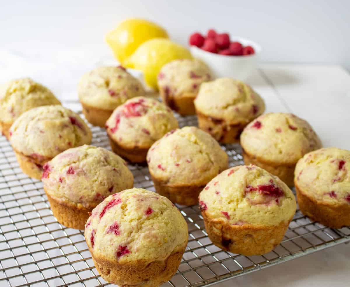 Freshly baked raspberry muffins on a baking rack.