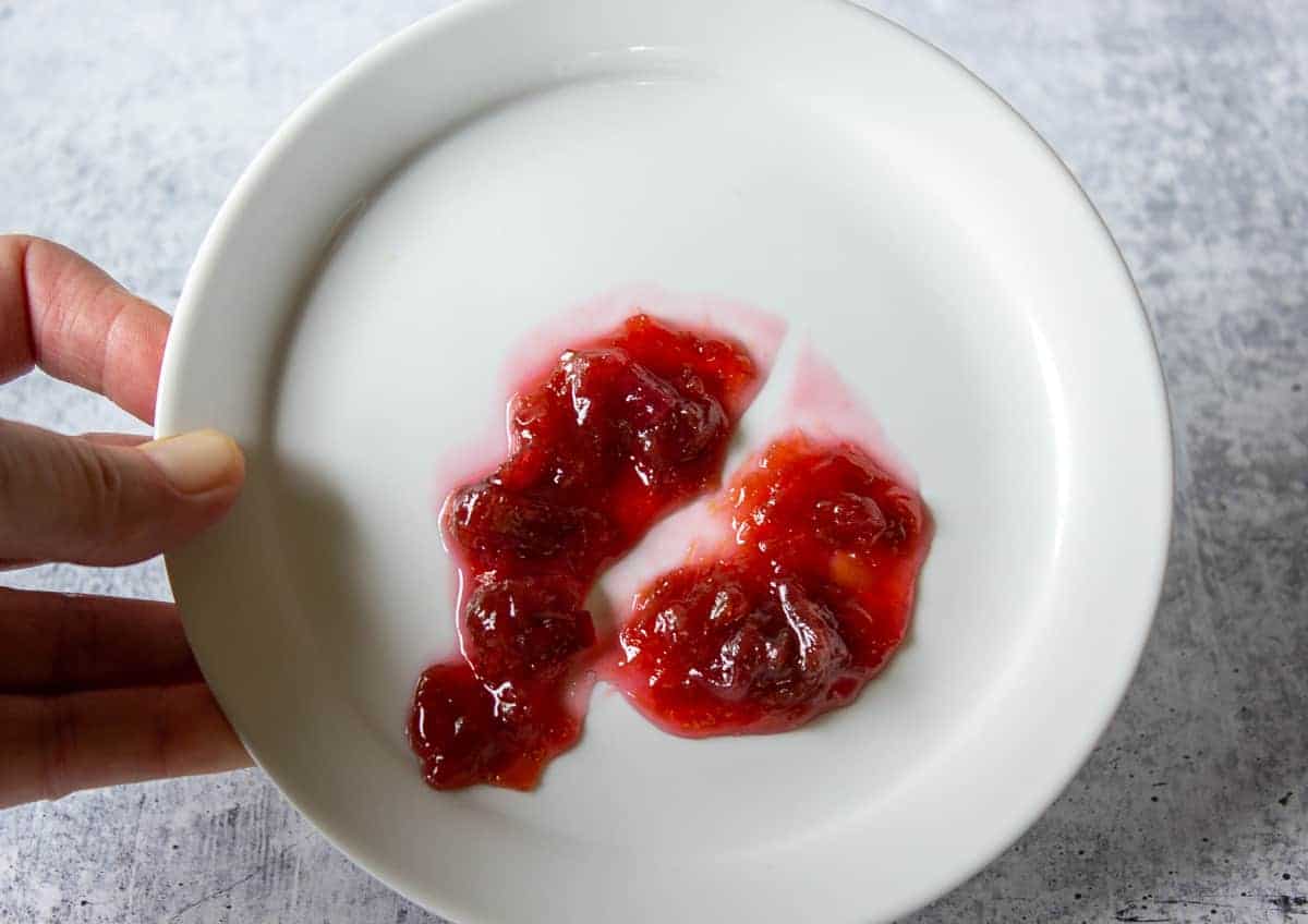 Rhubarb jam being tested on a white plate.