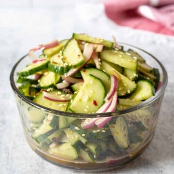 A glass bowl filled with cucumbers and onions.