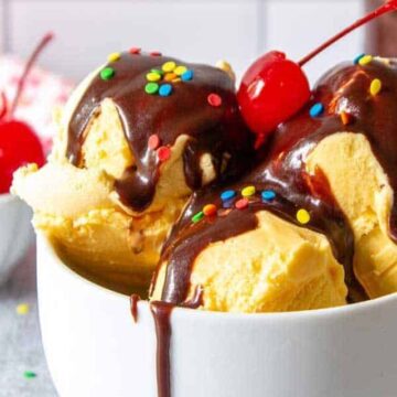 Scoops of vanilla ice cream topped with chocolate sauce and a cherry.