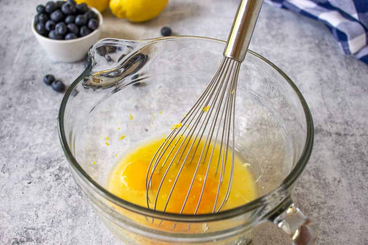 Egg mixture in a large glass bowl with a wire whisk. 